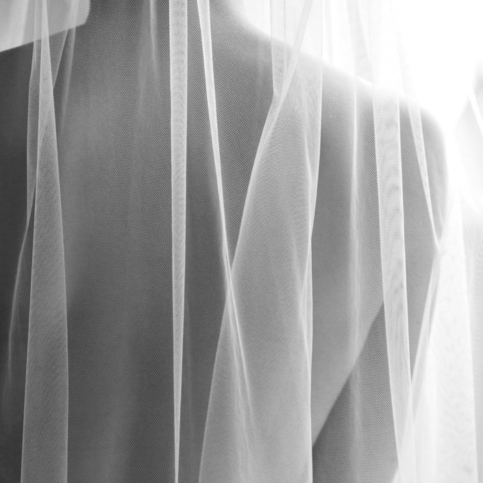 Photo noir et blanc cadrage serré du dos de la mariée seulement recouvert par son voile